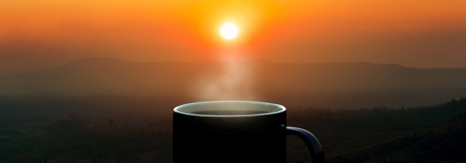 sun rising with coffee mug in foreground